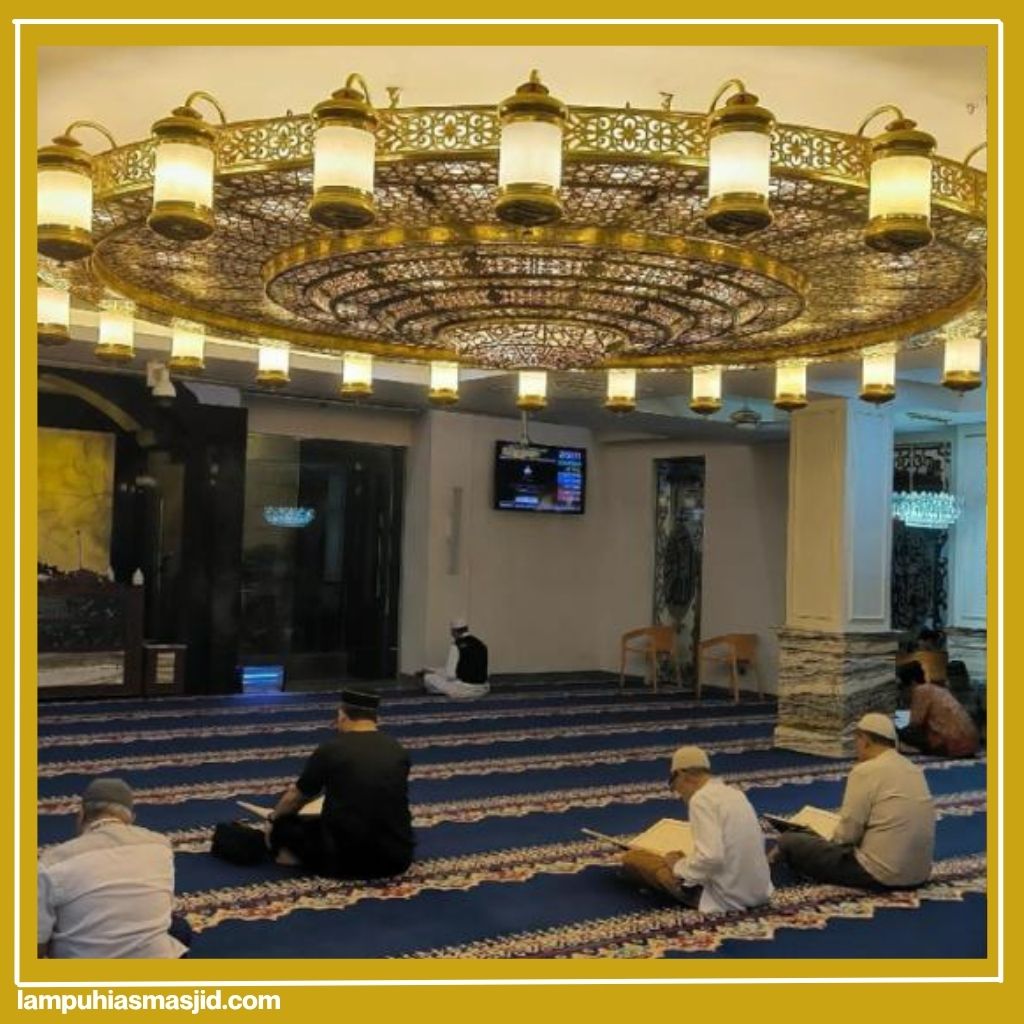 Jemaah membaca di ruang masjid dengan lampu gantung menyala